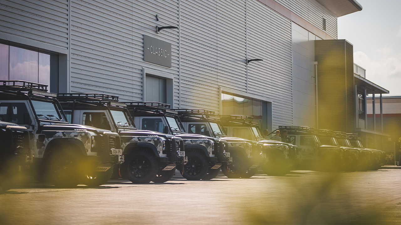 Row of Land Rover Defenders parked outside building marked &ldquo;CLASSIC&rdquo;.